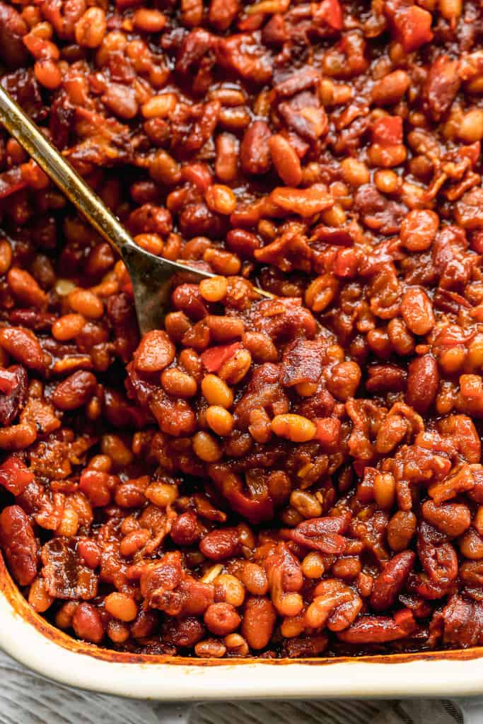 A spoon scooping baked beans from a dish.