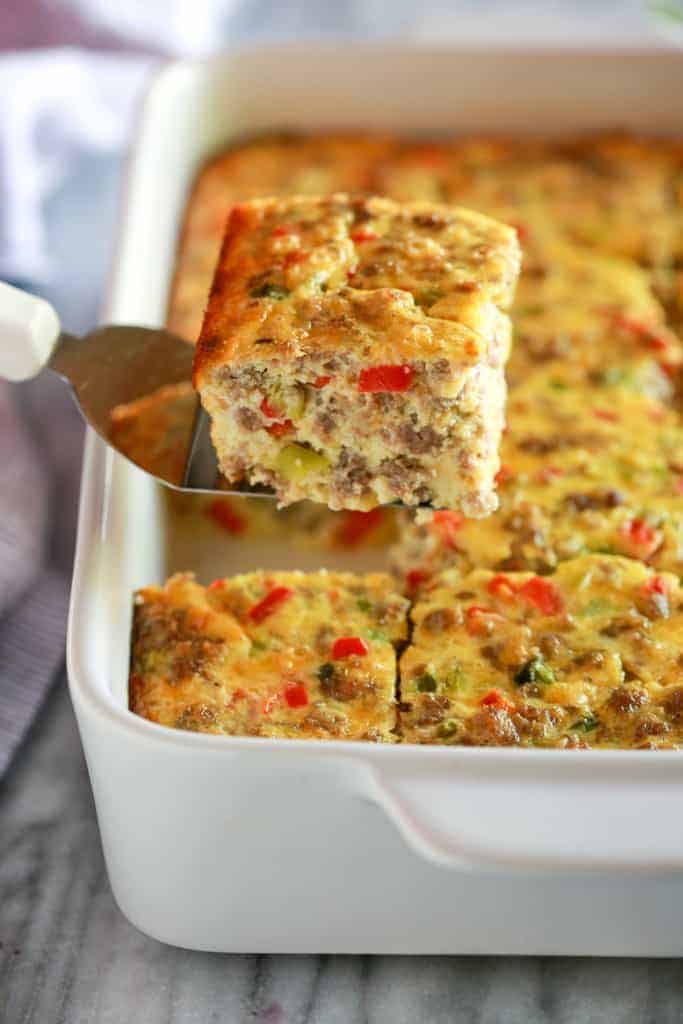 A spatula removing a slice of breakfast casserole from the pan.