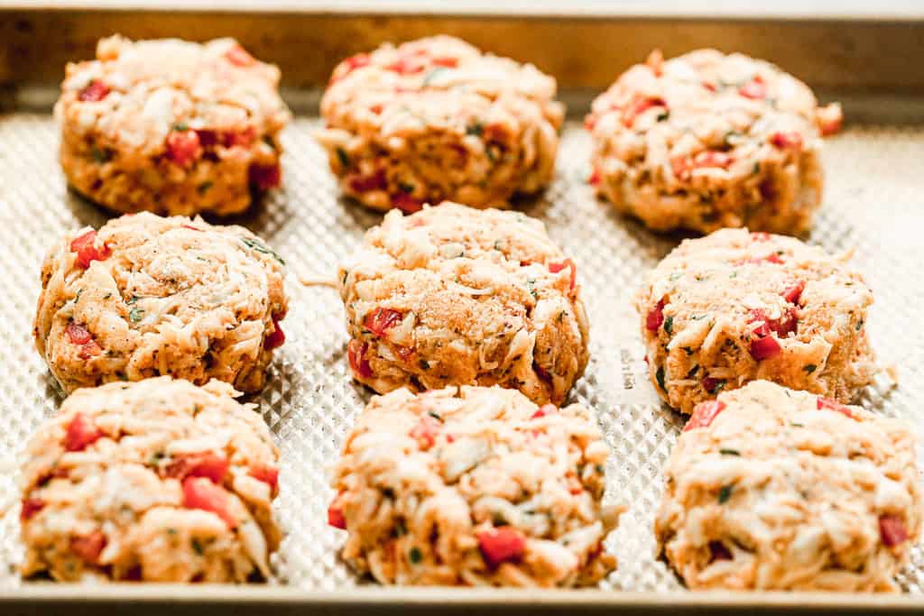 Crab cakes formed into patties, on a tray.