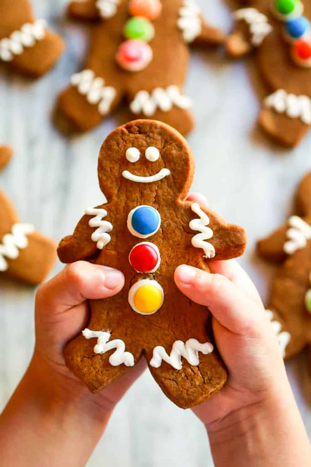 A child's hand holding a chewy gingerbread man cookie.