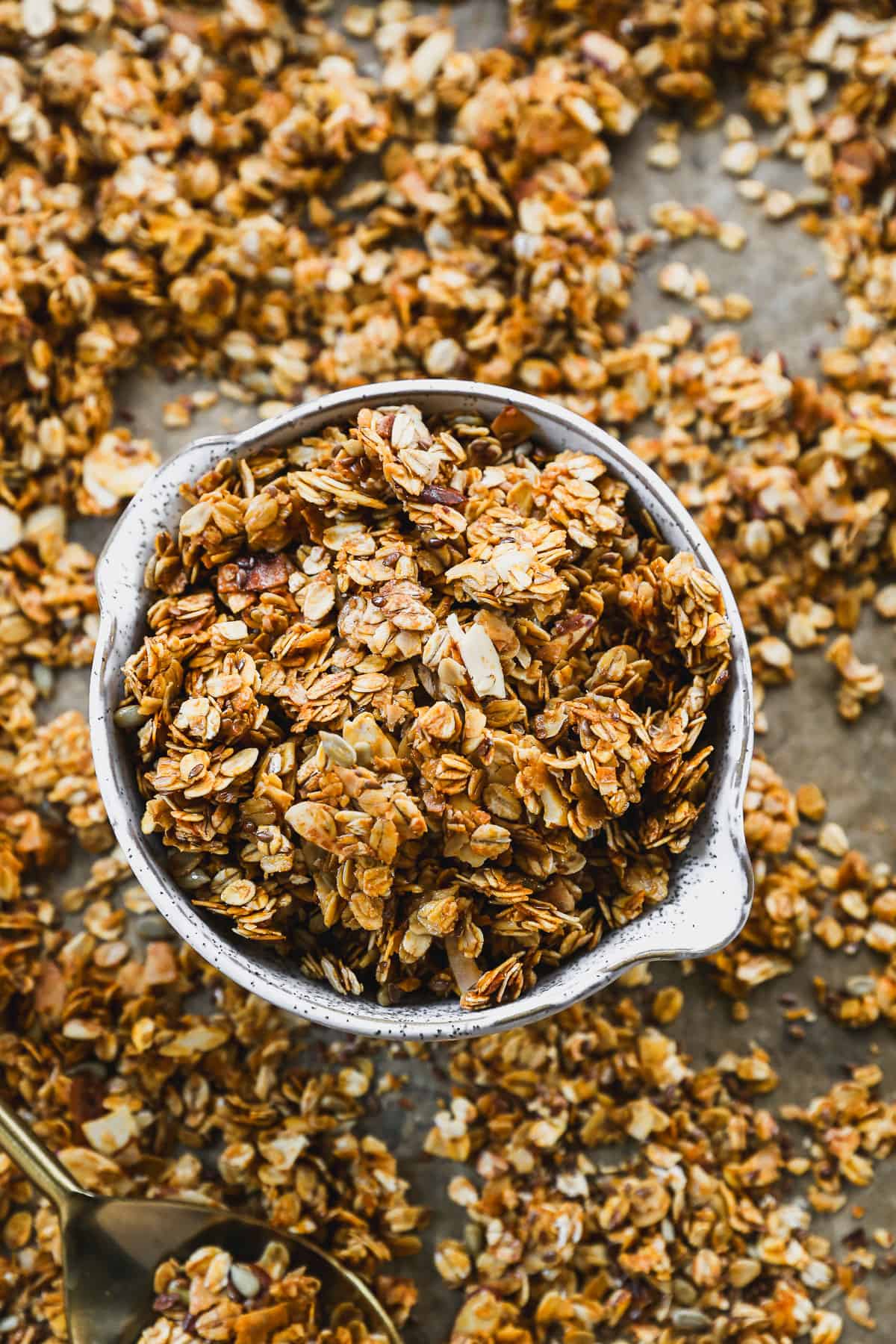A homemade granola recipe in a bowl on a sheet of baked, crunchy granola.