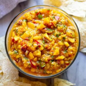 Mango Salsa served in a bowl surrounded by tortilla chips.
