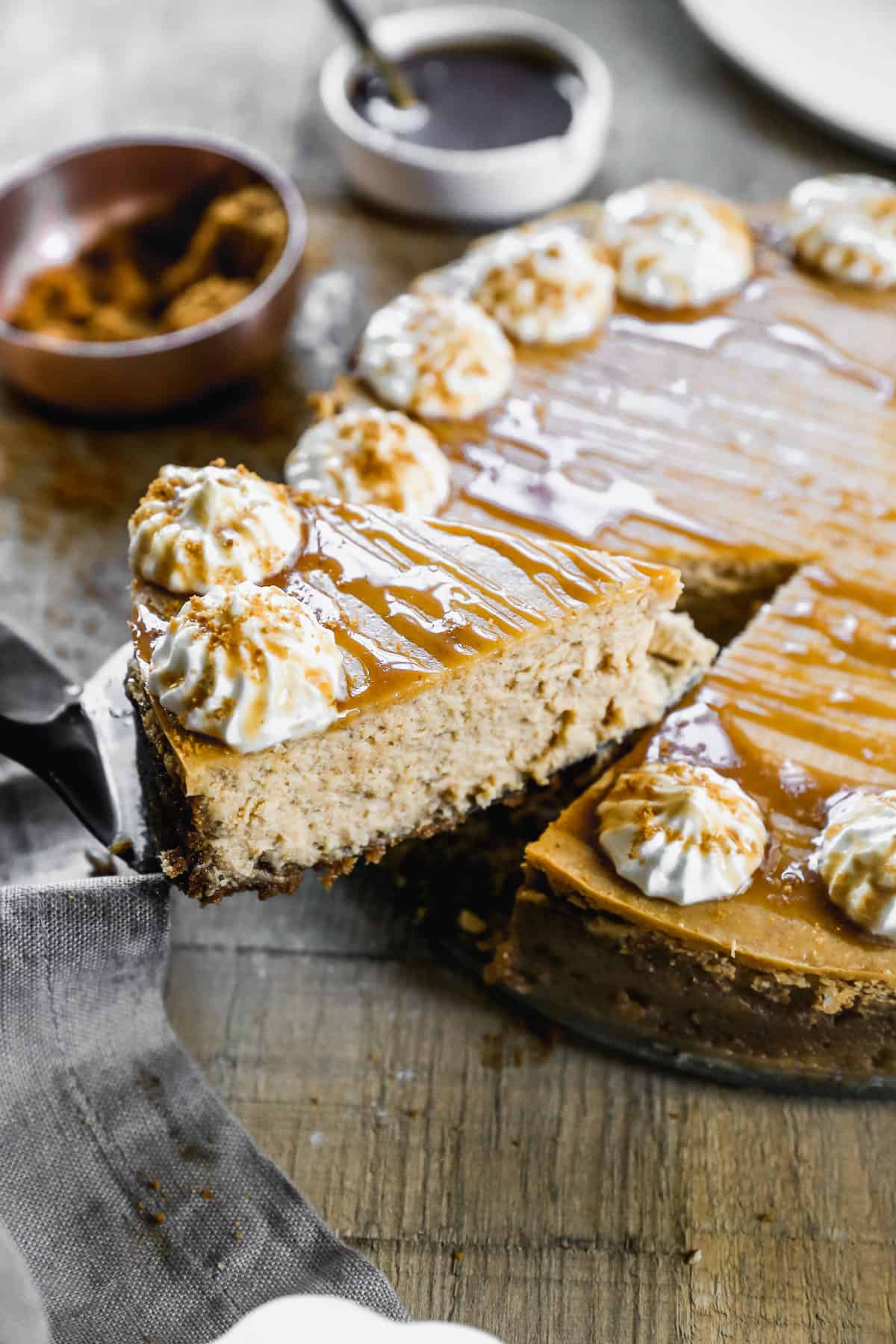 A slice of Pumpkin Cheesecake being lifted away from the whole cake.