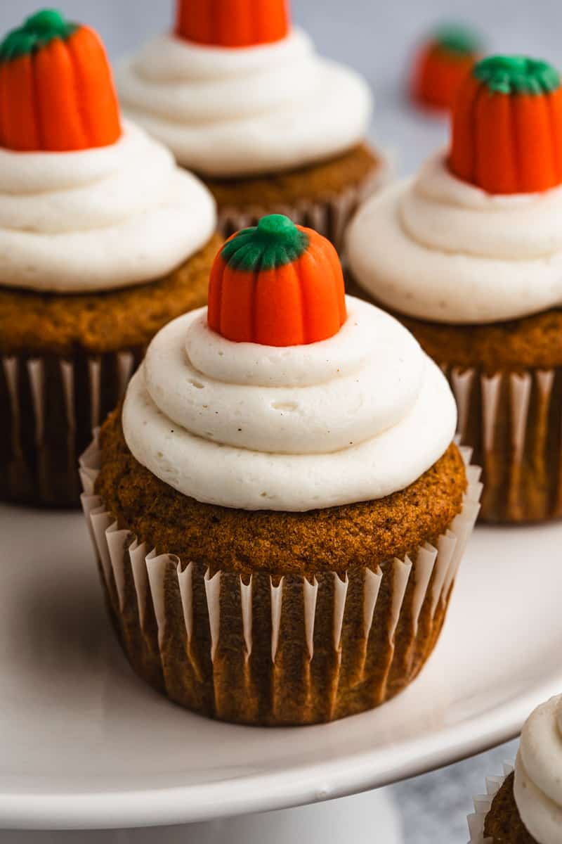 A moist Pumpkin Cupcake frosted with cinnamon cream cheese and topped with a candy pumpkin.