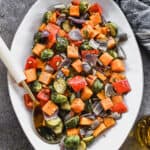 A serving dish filled with the best Roasted Vegetables: a mix of butternut squash, red onion, red bell pepper, and brussels sprouts.