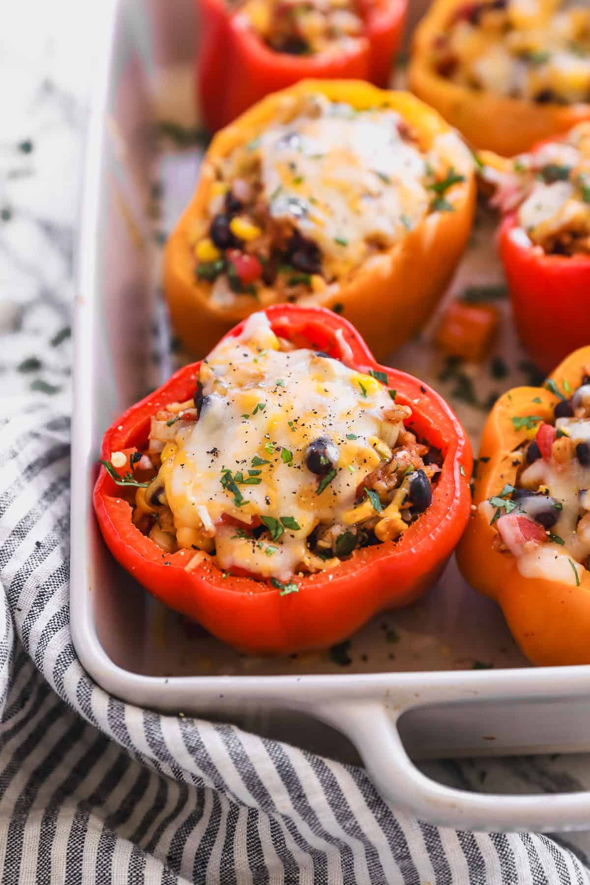 Easy vegetarian stuffed peppers in a baking dish, topped with melted cheese.